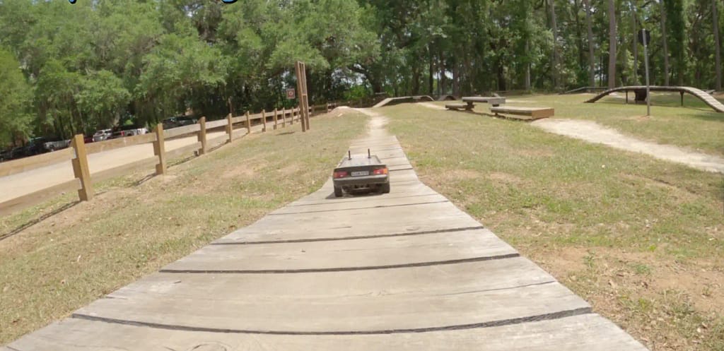 Tamiya TT-02 Celica ST165 driving down a wooden obstacle on a bike skills course