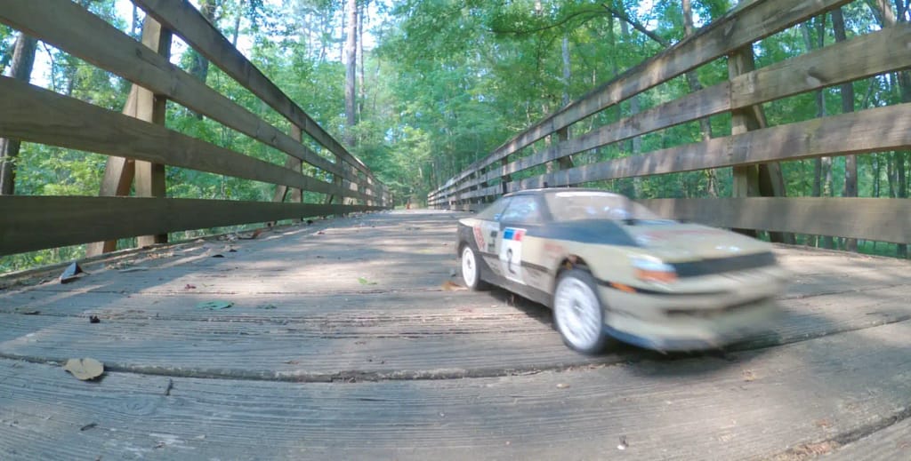 Tamiya TT-02 Celica ST165 rally car crossing a bridge on a dirt nature trail