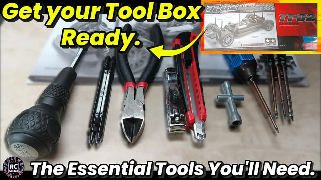 JIS screwdrivers, plastic nippers, hobby knife, nut drivers and hex drivers laid out as the essential tools for building a Tamiya TT-02 RC car.