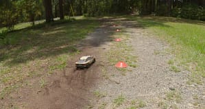 Tamiya TT-02 Celica ST165 driving through cones on a dirt and grass driveway